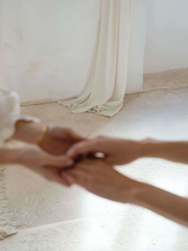 Hands meeting in a bright linen room